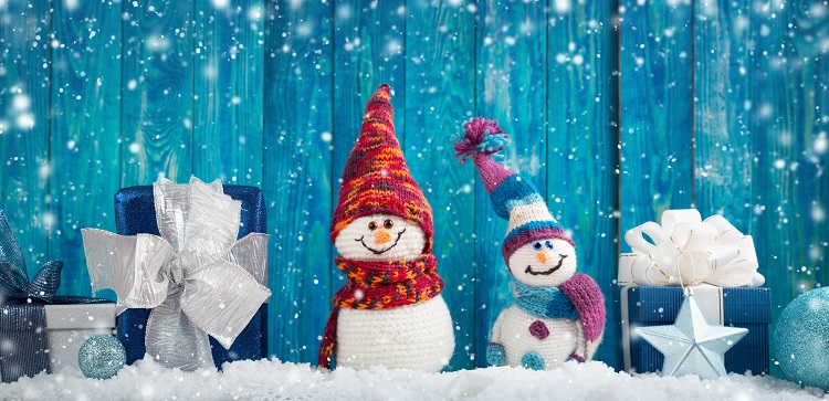 little knitted snowmans on soft snow on blue background